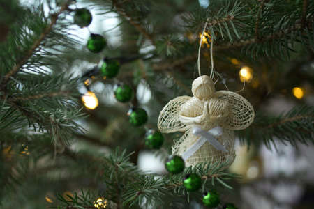 Christmas angel on christmas tree branch, lights hanging in a treeの写真素材