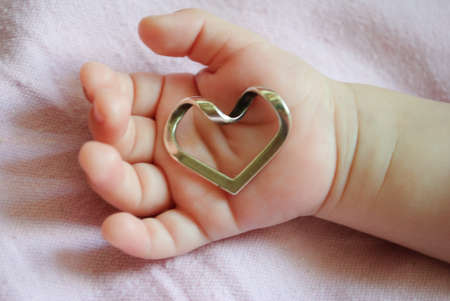 Babys hand holding a heartの写真素材
