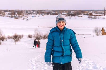 young boy in winter up the hill on the banks of the riverの写真素材