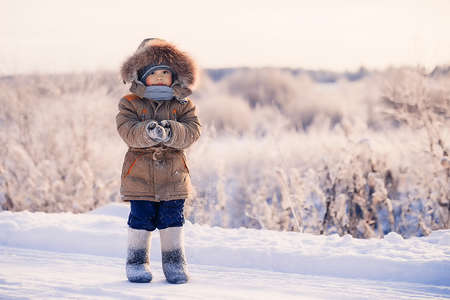Small boy in winter snow-covered road in the coldの写真素材