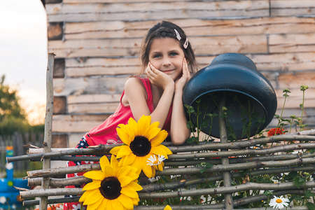 girl leaned on the fence next braided with flowers and a large cast-iron cauldronの写真素材