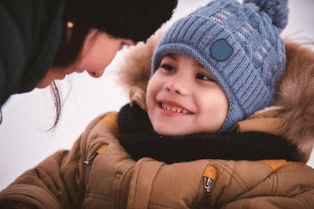 Little boy having fun outside with her mother in winterの写真素材