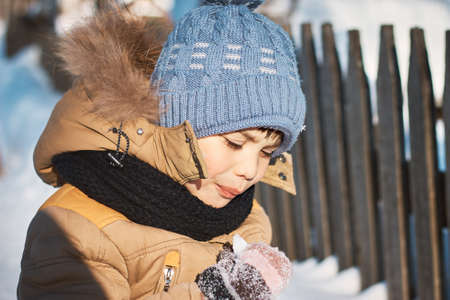 Little boy walks in the winter near the fence