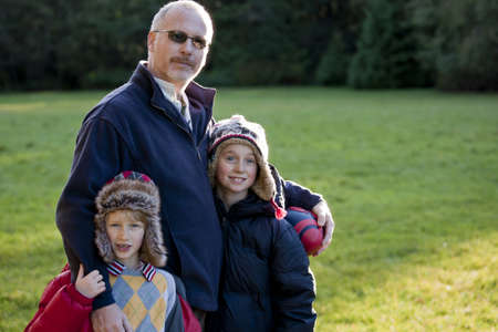 A fatehr and his two sons on fall day in the parkの写真素材