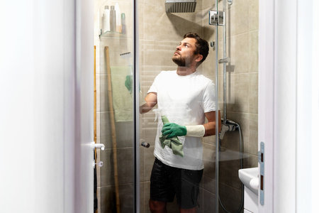 Man cleaning glass wall in shower room.の写真素材