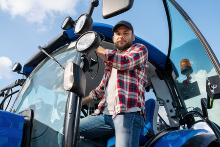 Young adult farmer posing next to his agriculture tractor.の写真素材