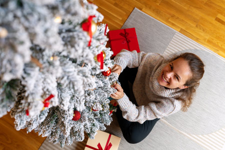 High angle view woman decorates the Christmas tree and smiling.の写真素材