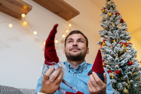 Adult man holding Christmas toy gnomes in his hand and remembers his childhood.