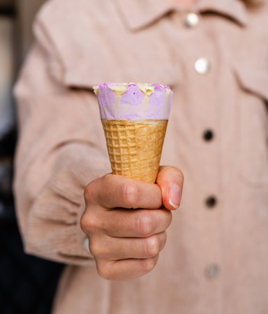 Ice cream cone in female hand close-up photo.