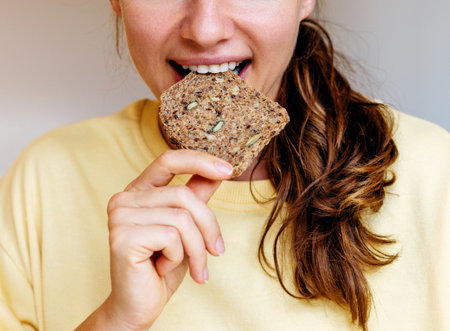 Woman eating grain bread close-up. Healthy eating and diet background.の写真素材