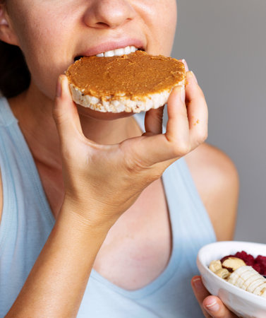 Female person eating healthy crispbread with peanut butter close-up.の写真素材