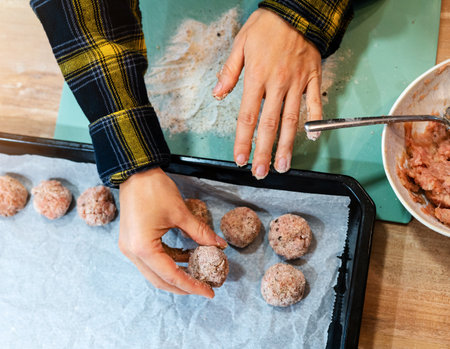 Meatball in female hand while cooking. Cooking handmade meatballs.の写真素材