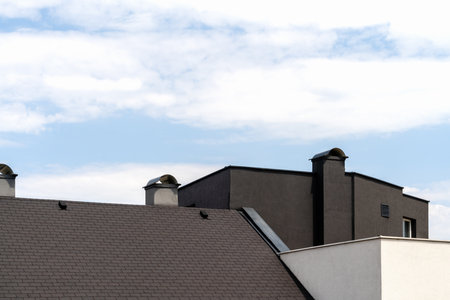 Black coloured roof of residential building in front of sky in Europe.
