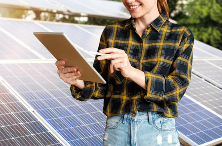 Female engineer checks the technical condition of solar panels using a digital tablet.の写真素材