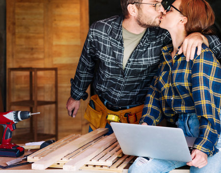 Family small local business and celebration success. Husband kisses his wife during the work in their workshop.の写真素材