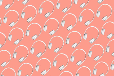 Modern pattern of white wireless headphones on peach coloured background.の写真素材