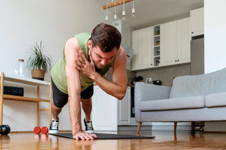 Home workout. Man does arms curling exercise in plank position.の写真素材