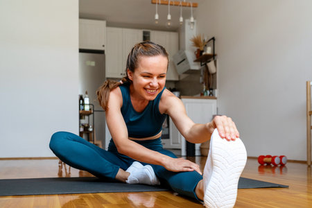 Caucasian female wearing sportswear doing stretching exercise at home.