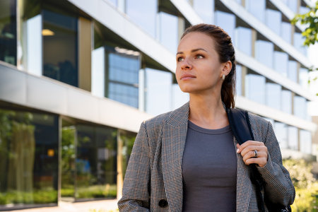 Human resource, labor and employment. Female woman wearing smart casual clothes stands outdoors in front of office building.の写真素材