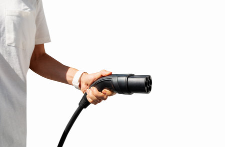 Isolated black EV charging plug in female hand. Electric car charging connector.