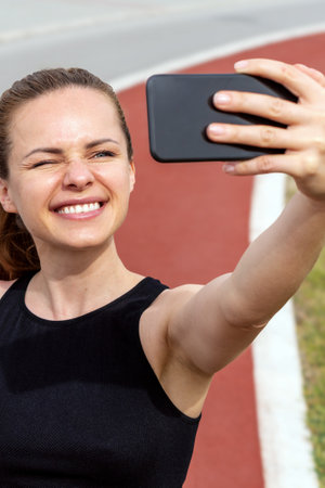 Healthy and happy female athlete taking a selfie with smartphone on a city running pathの写真素材