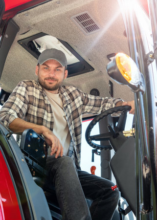Vertical portrait of man agricultural or construction tractor driver in countryside.の写真素材
