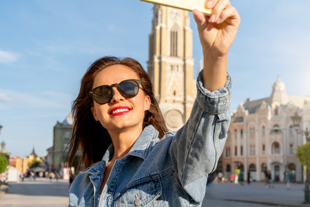 Young brunette woman tourist taking a selfie in front of a local sight.の写真素材