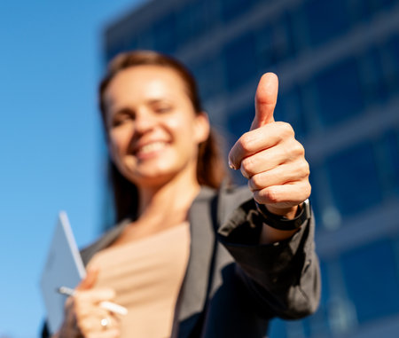 Defocused modern businesswoman giving a thumbs-up to the cameraの写真素材