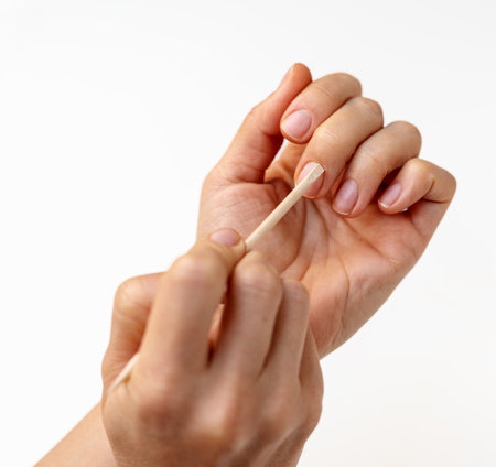 Woman using wooden cuticle pusher during nail care at home. Pushing back cuticlesの写真素材