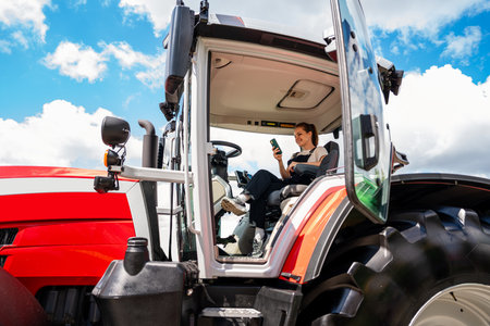 Female worker using smartphone inside tractor cabinの写真素材