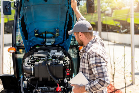 Farm male mechanic performing tractor engine inspection