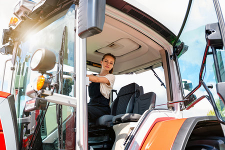Female agricultural worker operating tractor outdoors. Woman in farmingの写真素材