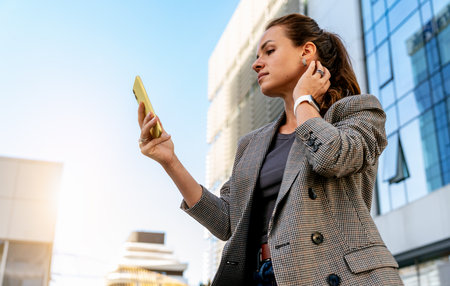 Modern female in the city looking at smartphone like a mirrorの写真素材