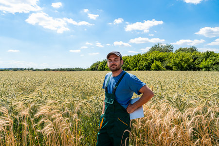 Rural man with tablet standing among cereal crops in growing season