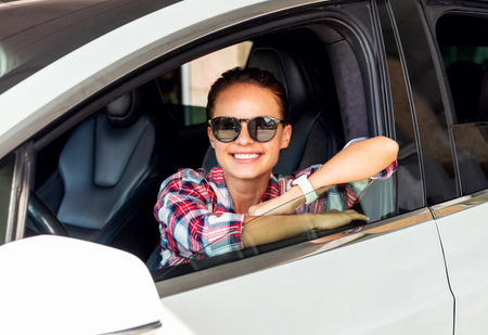 Cheerful woman sitting in her new car at dealership