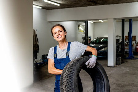 Young female worker carrying tyre at tyre fitting serviceの写真素材