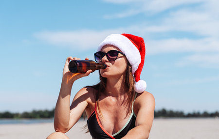 Relaxed woman on beach during Christmas vacation, drinking beerの写真素材