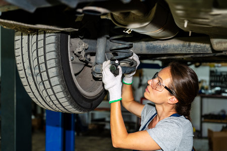 Female auto mechanic working at car repair garage.