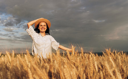 Young female in straw hat walking on rural field.の写真素材