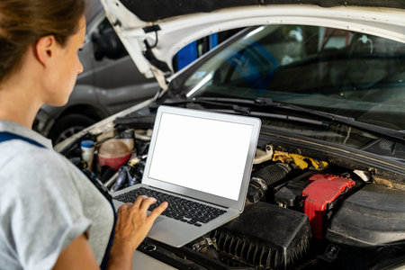 Mockup blank screen of laptop in hands of female auto mechanic in front of car.の写真素材