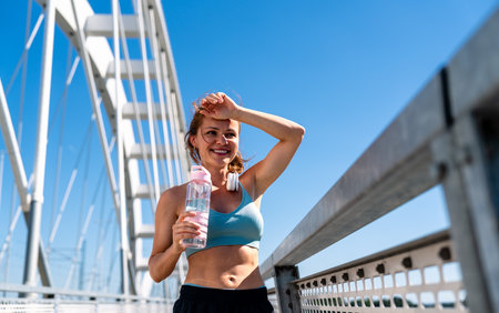 Fit woman with water bottle during outdoor workout in urban environment.の写真素材