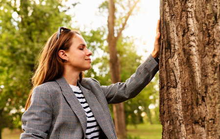 Mindful urban woman touching tree and connecting with nature outdoors