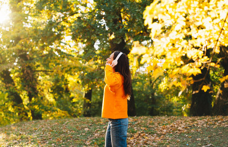 Happy woman walking among autumn trees listening to music with headphonesの写真素材