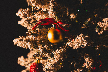 Close-up of golden Christmas bauble ornament hanging on Christmas tree branch on dark backgroundの写真素材