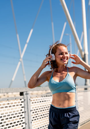 Happy fit woman wearing wireless headphones enjoying morning jog outdoors in summer.の写真素材