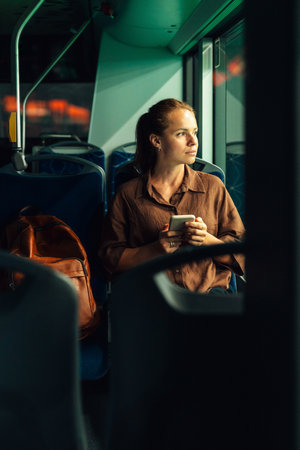 Woman with smartphone commuting at night by city busの写真素材