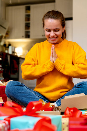 Happy surprised woman unwrapping Christmas gifts at home.の写真素材