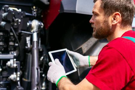 Farm machinery technician using tablet for equipment diagnosticsの写真素材