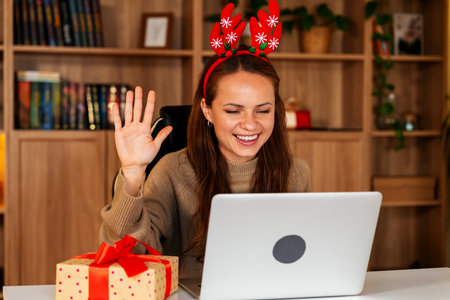Cheerful wearing reindeer antlers waving hand during online meeting with family.の写真素材