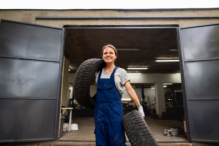 Woman employee carrying tires at local auto repair shopの写真素材